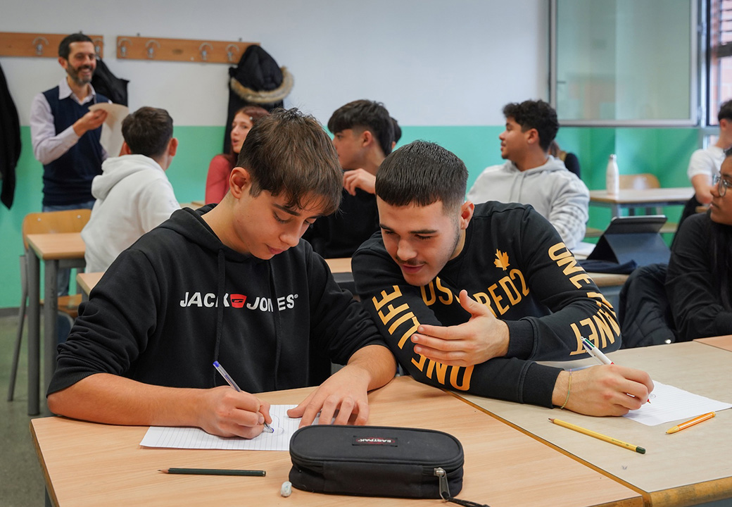 Due ragazzi scrivono su un foglio in un aula scolastica