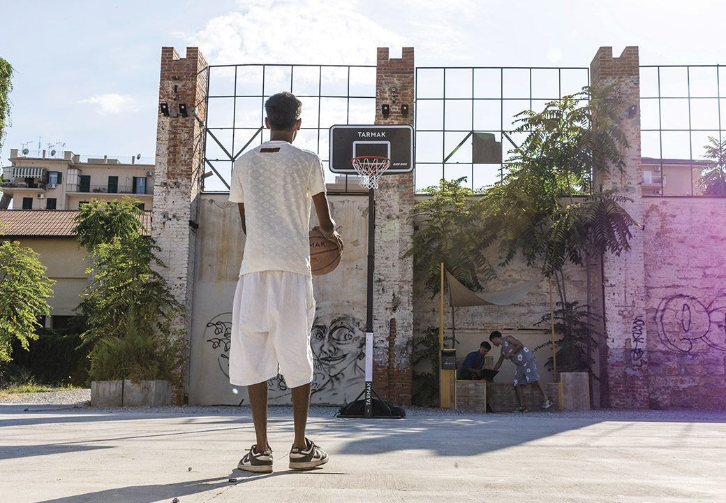 Ragazzo tira a canestro in un campetto da basket all'aperto
