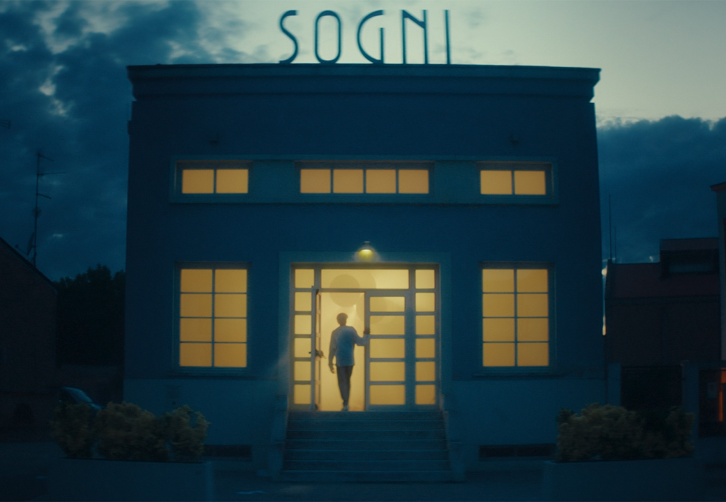 Un uomo entra in un edificio con sopra un'insegna con scritto "Sogni"