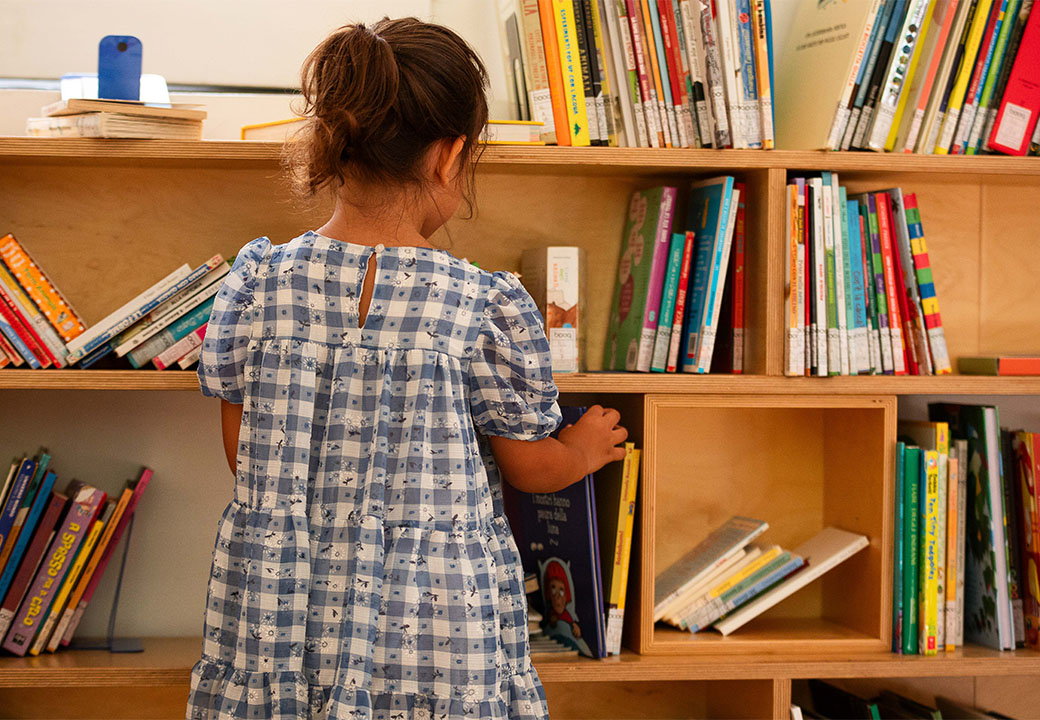 Una bambina sceglie un libro da uno scaffale