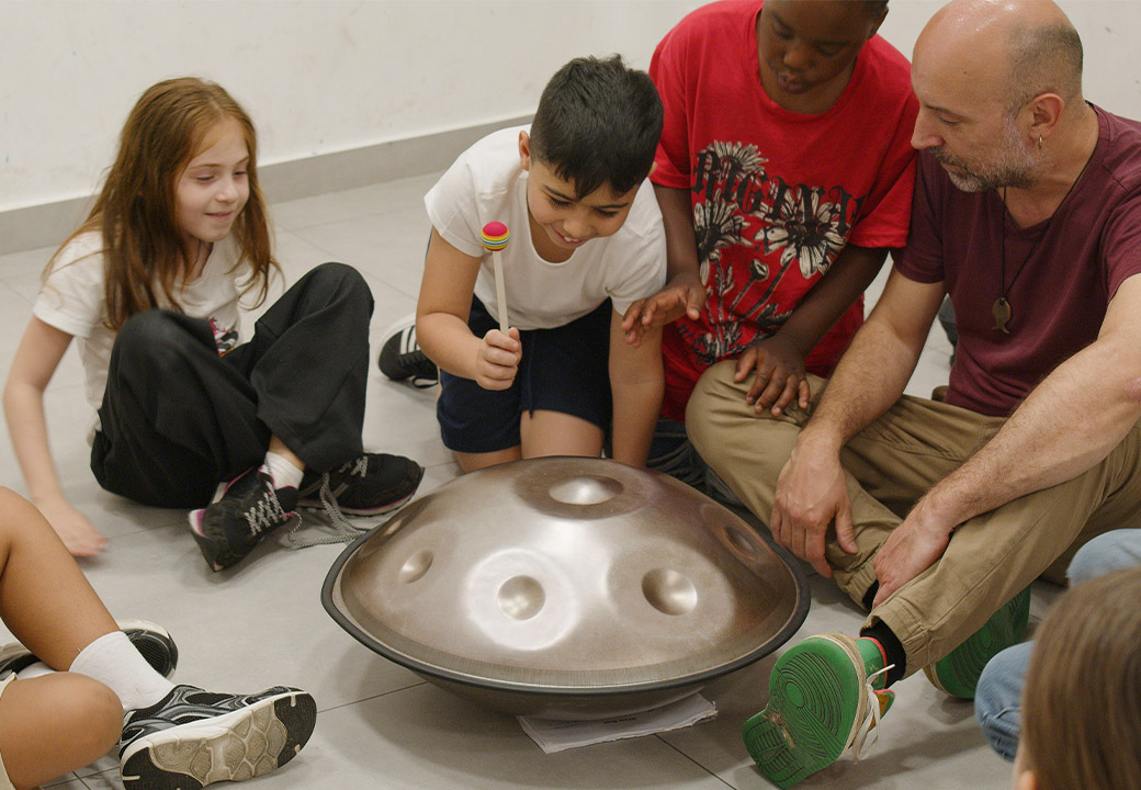 Alcuni bambini suonano uno strumento a percussione con un educatore