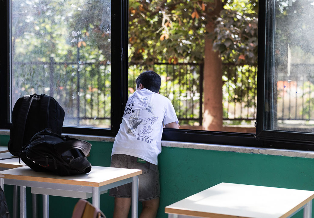 Un bambino guarda fuori dalla finestra di un'aula scolastica