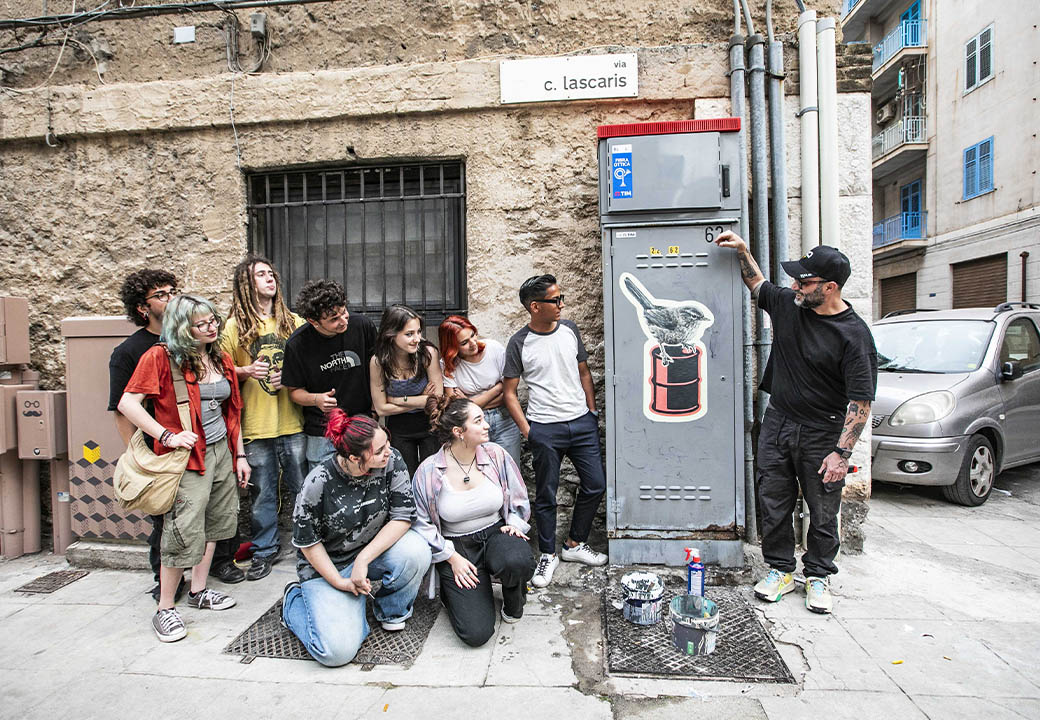 Un gruppo di ragazzi e ragazze osserva un'opera di street art