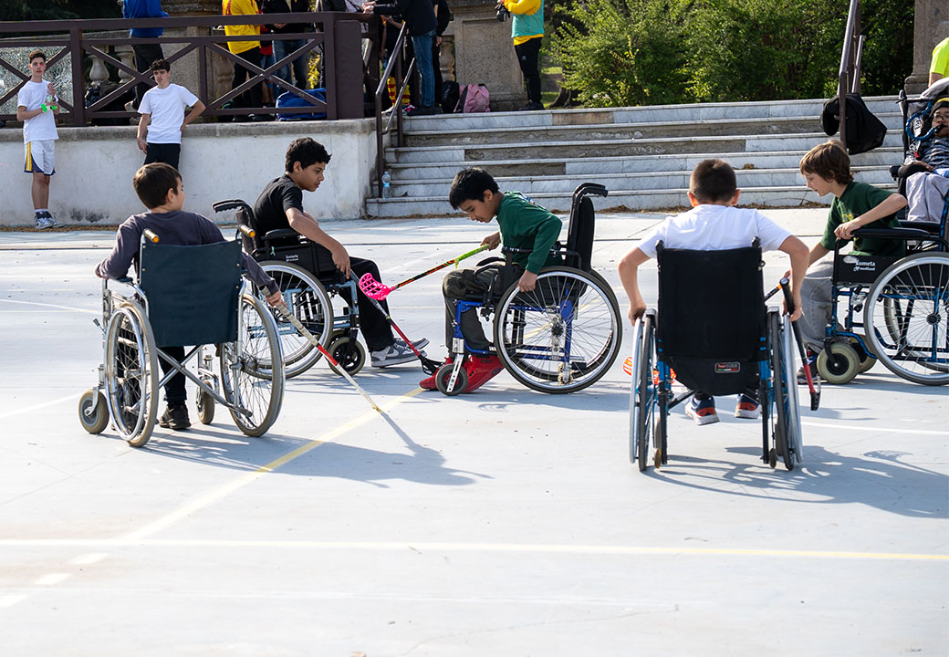 Alcuni ragazzi in carrozzina giocano a hockey in un campo all'aperto