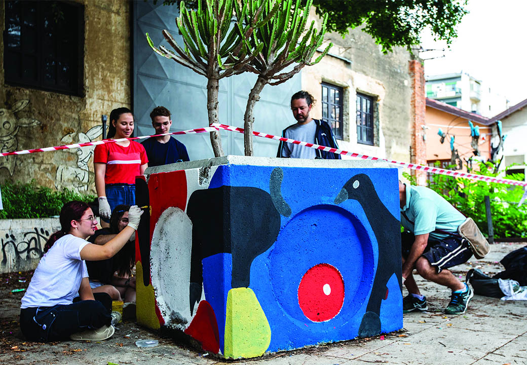 Ragazzi dipingono e decorano un arredo urbano