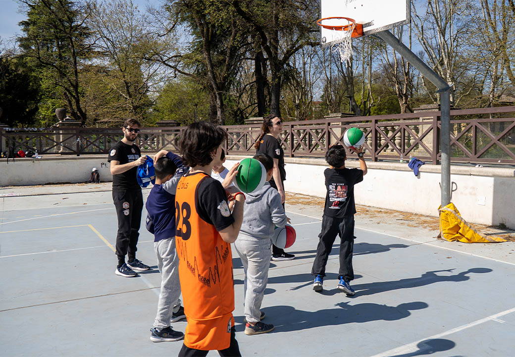 Dei bambini imparano a giocare a basket in un campetto all'aperto