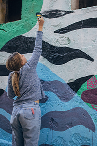 Ragazza dipinge un murales colorato