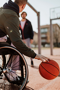 Ragazzo in carrozzina gioca a basket con gli amici